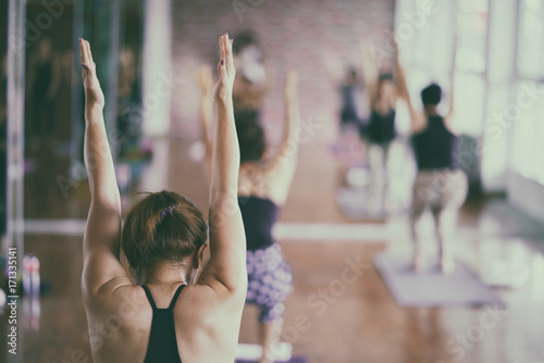 Group of asian young woman stretching and practices practicing during their yoga class in a gym. fitness, sport, training, yoga and people concept