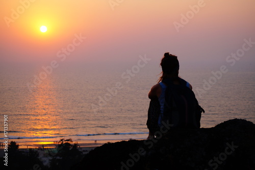 Girl sitting on the edge of the hill, sunset time, sea view