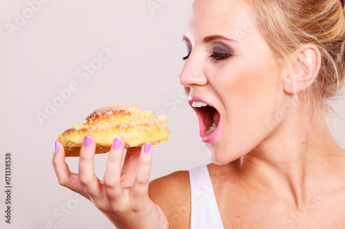 undecided woman holds cake sweet bun in hand