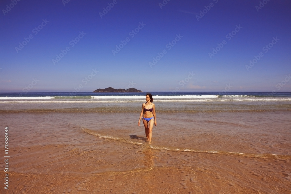 mid age woman in swimsuit walking on beach, Brazil