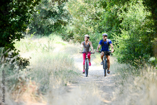 happy young couple riding bicycle in countryside during summer