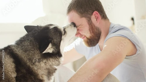 Hipster man snuggling and hugging his dog close friendship loving bond between owner and pet husky