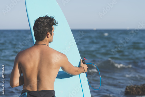 Surfer holding his blue surfboard