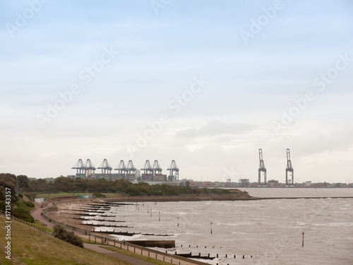 sea industry cargo and shipping cranes in the distance beach groynes Harwich Port