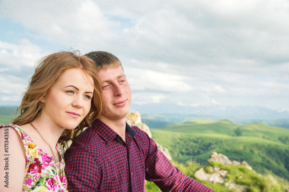 View from the back. Young couple hugging kisses against the blue sky and white clouds.