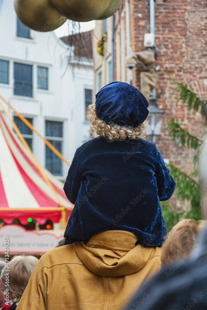 Nice little boy with blond curls sitting on the shoulder of his father during the Dickens Festival