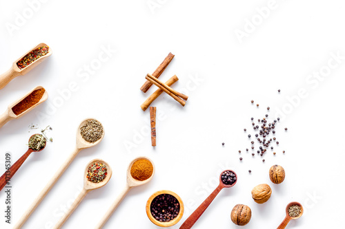 Variety of spices and dry herbs in spoons on white kitchen table background top view mock-up