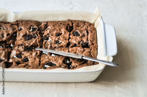 Dark chocolate brownie squares with Oreo on a white baking dish