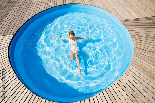 Top view on the round water pool with woman swimming outdoors