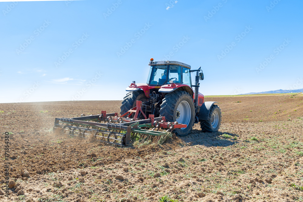 Fototapeta agricultural tractor in the foreground with blue sky background.