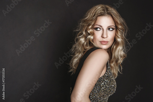 studio portrait of a beautiful blonde girl with curly hair on dark background