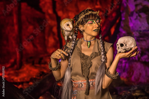 Beautiful witch with the white owl and skull in the hand.