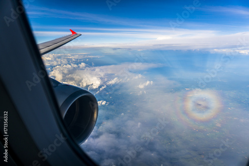 Wing of an airplane with the plane's shadow and a circular rainbow