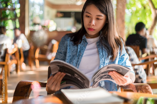 Young asian woman reading book in coffee shop. photo