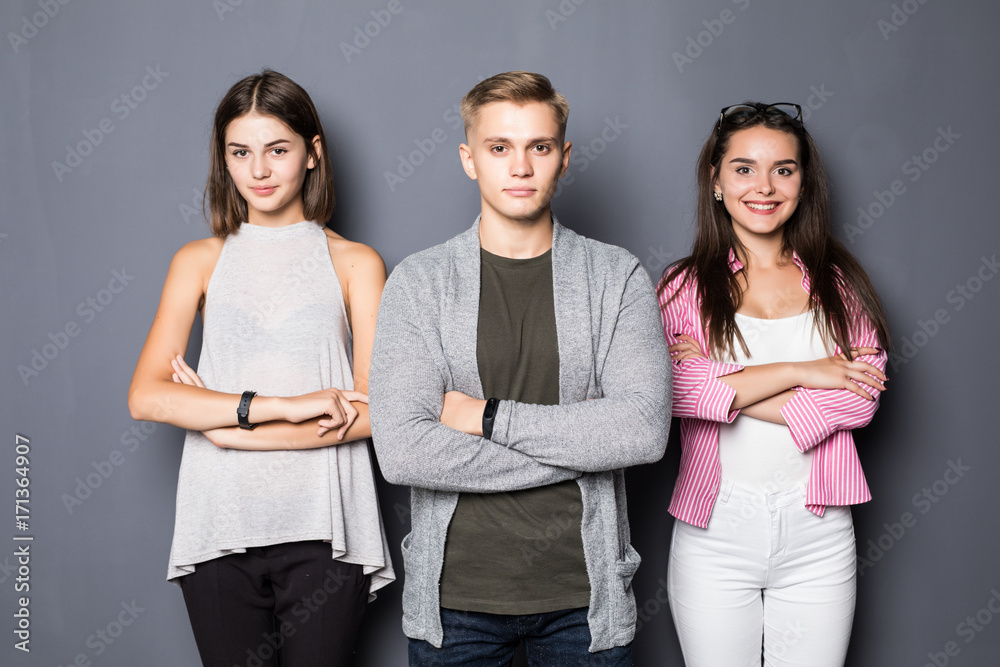 Obraz premium Happy young friends standing indoors on gray background