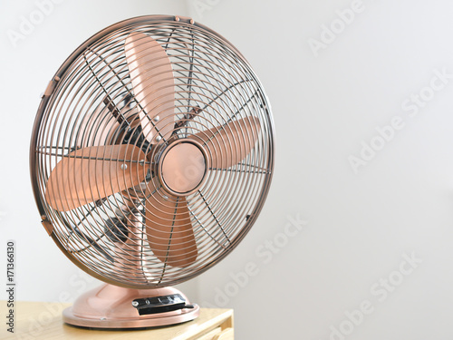 Rose gold colored traditional electric fan in a home.
