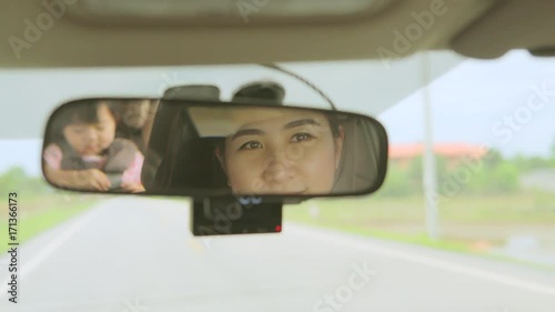 Asian Mother driving a car, having her little baby girl in a child seat
