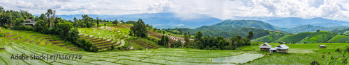 A panorama view of local houses and Rice terrace in a cloudy lighting surrounded by trees and mountains with a raining storm in the background at Pa Bong Piang  Mae Chaem, Chiangmai, Thailand...
