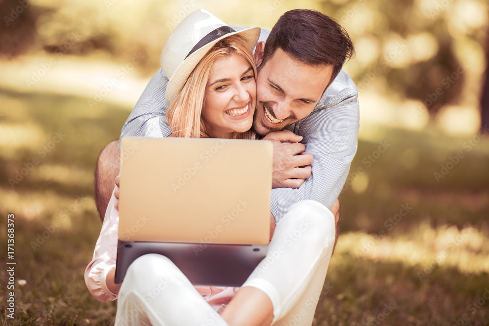 Attractive couple using a laptop in a park. Attractive couple using a laptop in a park.