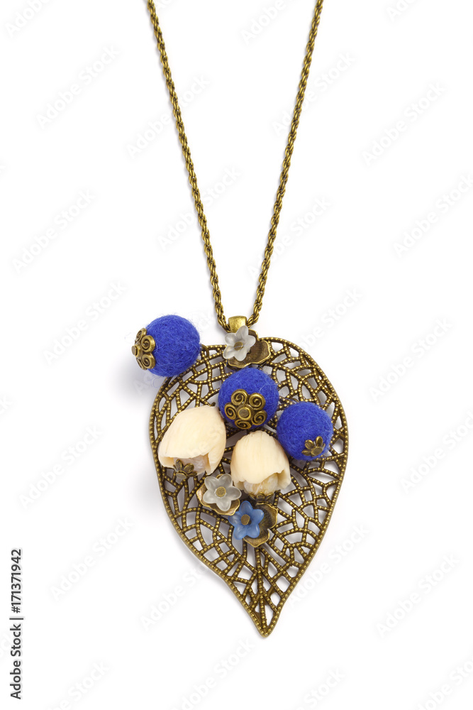 Pendant handmade on a chain in the form of a metallic openwork leaf and decorative flowers on a white background
