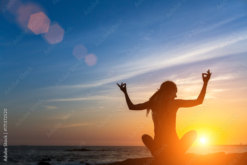 Yoga fitness silhouette. Meditation woman on the ocean during beautiful sunrise.