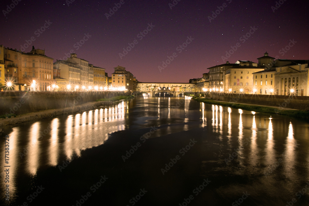 View down the Arno River to Ponte Vecchio at night in Florence, Italy