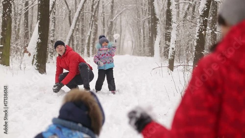 Young family in red jackets and their little daughter and son play in the snow in winter Park. photo