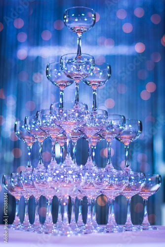 Pyramid of glasses champagne on wedding party. Champagne tower. Glass of tower in blue background.