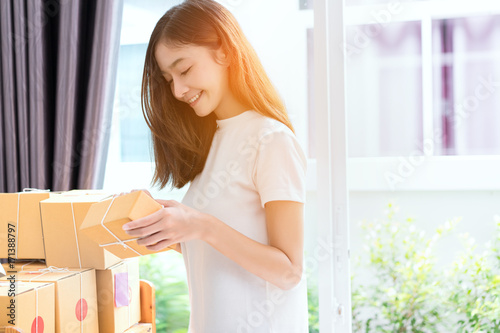 Young asian girl freelancer business owner working at home office with note, post it, packaging sort box delivery online market on purchase orders to customer.