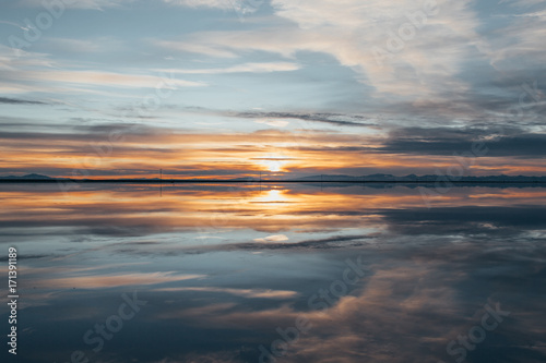 Symmetry view of Bonneville Salt Flats against cloudy sky at sunset photo