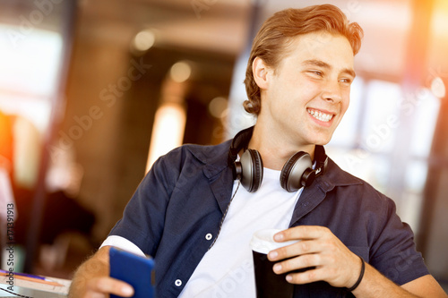 Confident young man in smart casual wear holding phone