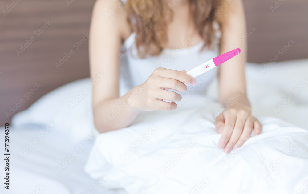 Selective focus Pregnancy test positive result on hand of young woman in her bedroom,Blurred background. Selective focus Pregnancy test positive result on hand of young woman in her bedroom,Blurred background.