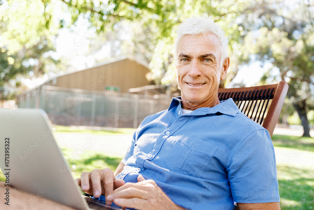 Senior man with notebook sitting in the park Senior man with notebook sitting in the park