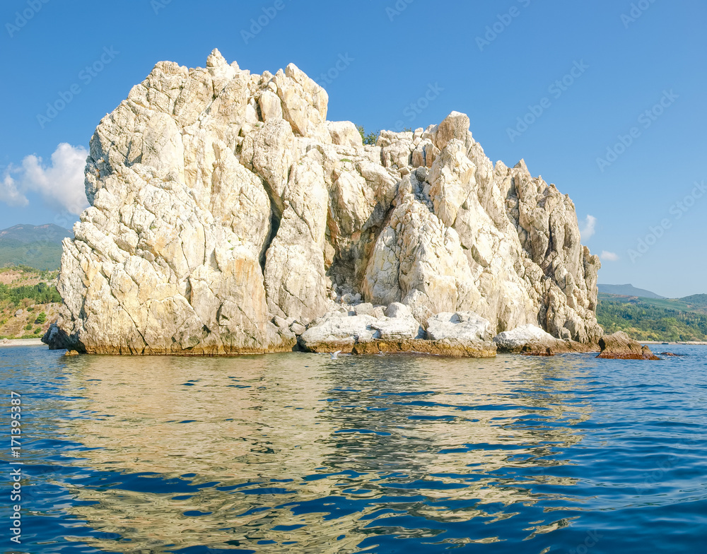 Single limestone rock in the sea near the shore