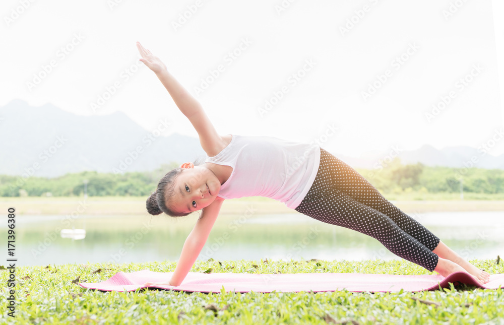 Fototapeta premium Happy cute girl practices yoga and meditates in the lotus position