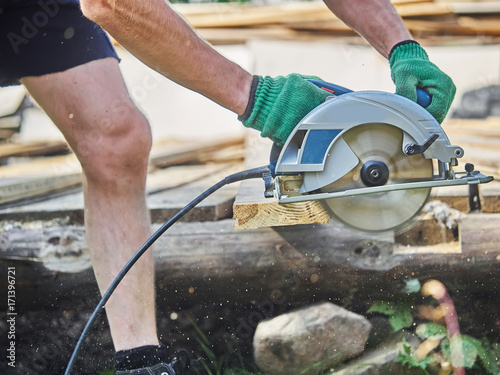 The builder cuts the board with a circular saw