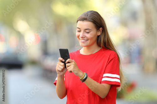 Happy teen texting on phone on the street