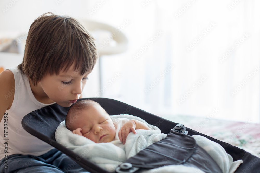 Beautiful boy, hugging with tenderness and care his newborn baby brother at home Beautiful boy, hugging with tenderness and care his newborn baby brother at home
