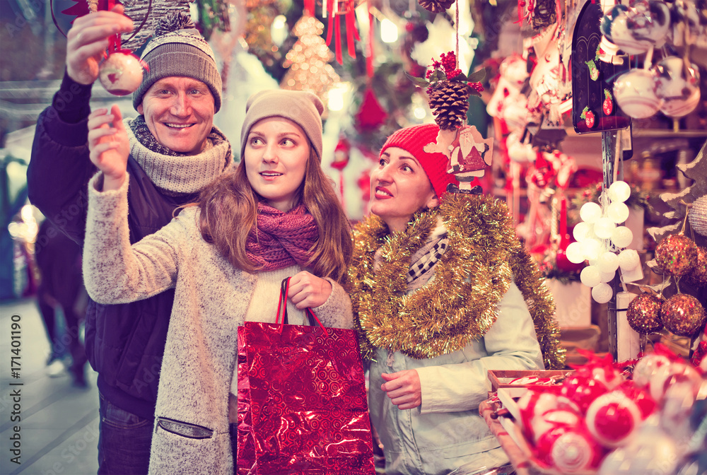 happy family couple with teen daughter choosing Christmas decoration