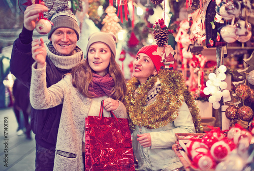 happy family couple with teen daughter choosing Christmas decoration