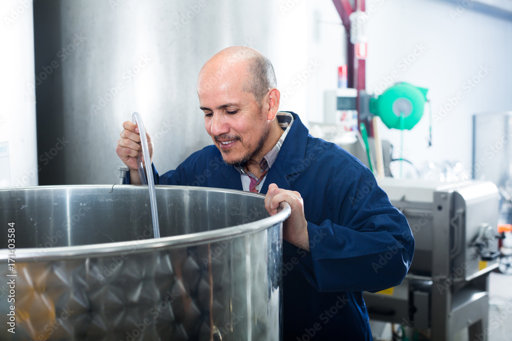 Fototapeta premium mature man working in wine fermentation section.