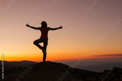 Silhouette of happy joyful young attractive woman playing yoga and having fun at the mountain against the sunset. Freedom  sport  adventure and leisure vacation concept.