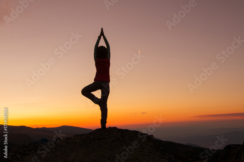 Silhouette of happy joyful young attractive woman playing yoga and having fun at the mountain against the sunset. Freedom, sport, adventure and leisure vacation concept.