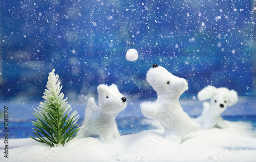 Christmas and New Year. White cute cheerful doggies play in snowballs near Christmas tree on a blue background. Creative festive layout for congratulatory text. Template for a festive greeting.