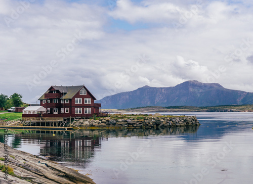 Red wood small house on the stone seascape with background of sky with clouds. By Letowa.