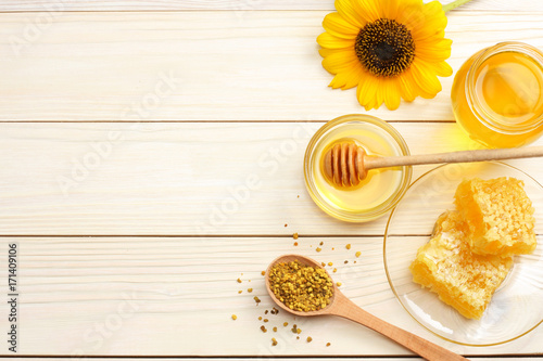 Sunflower with honey, Honeycomb and honey dipper on light wooden table. Top view with copy space