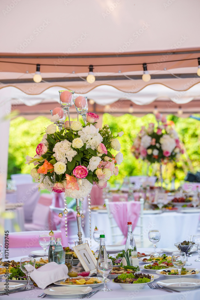 Served round banquet table outdoor in marquee decorated pink flowers and silk
