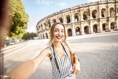 Photography Young woman tourist making selfie photo in front of the ancient amphitheatre in