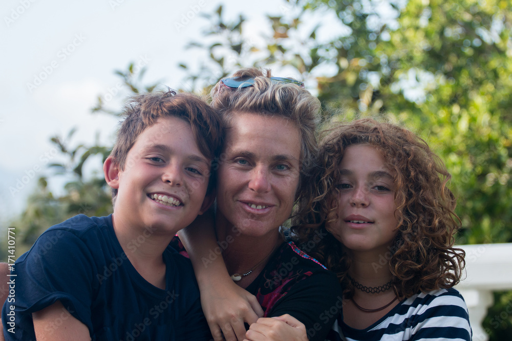 Happy family composed of a mother and her two children, a boy and a girl photographed in a garden during the summer