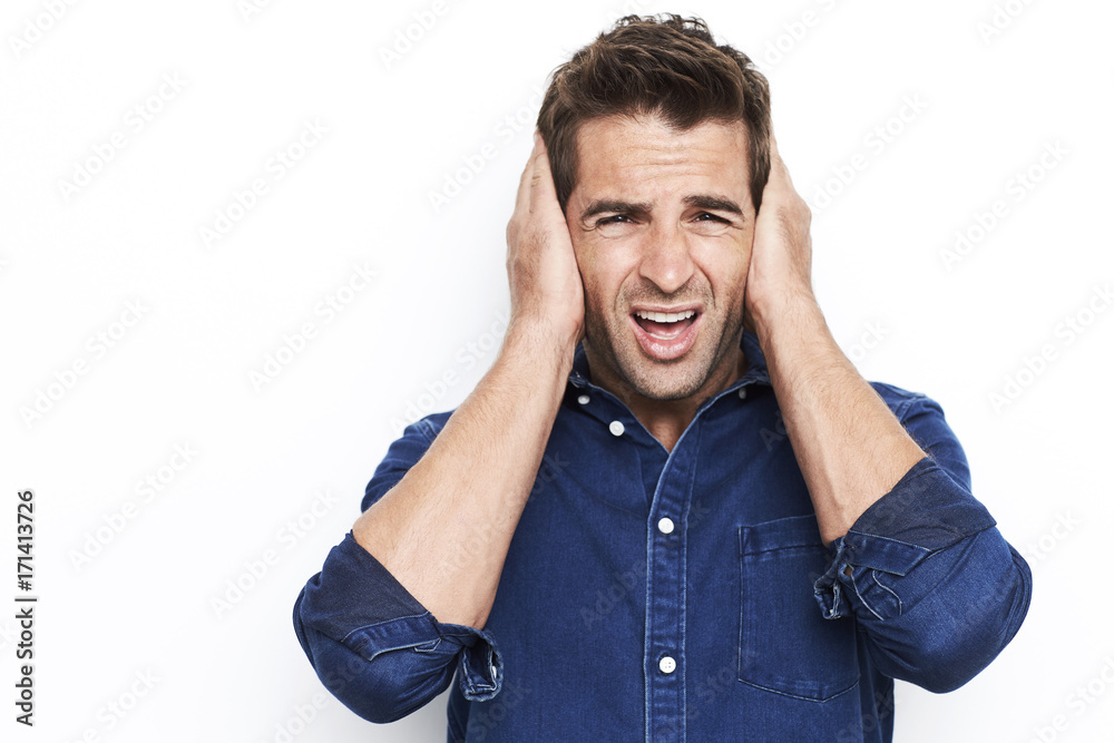 Guy in studio with hands over ears, portrait